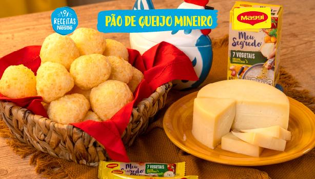 Imagem da receita de pão de queijo servido em uma cesta ao lado de um queijo e de uma galinha azul