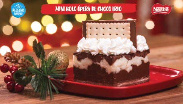 Fotografia de um bolo com três camadas com chantilly e um biscoito no topo. O bolo está sobre um prato vermelho.