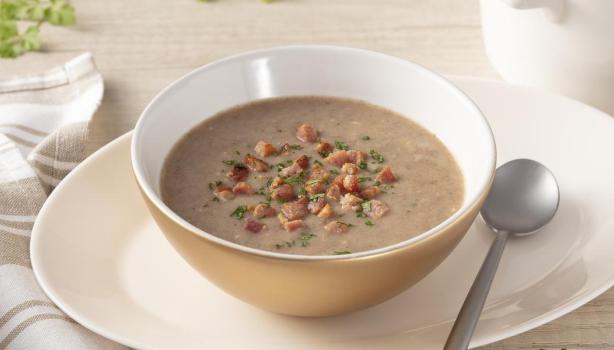 As melhores comidas de Inverno Sopa de feijão na tigela em cima de um prato, ao lado uma colher