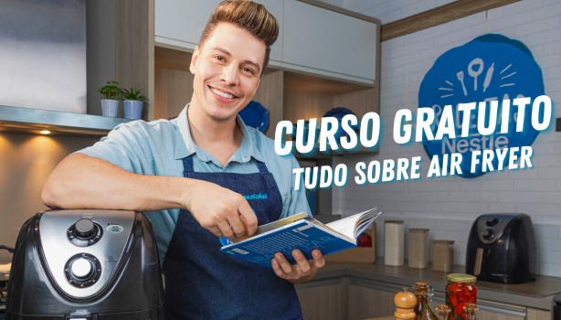 Fotografia mostra um rapaz apoiado sobre uma air fryer, segurando um livro.