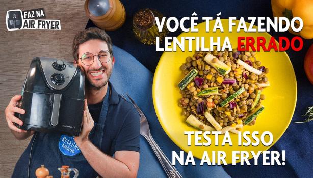 Fotografia mostra homem segurando air fryer e prato de lentilha no fundo.
