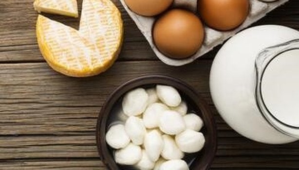 Ovos em bandeja e três tipos de queijo em uma tábua. A imagem representa os alimentos ricos em K2.