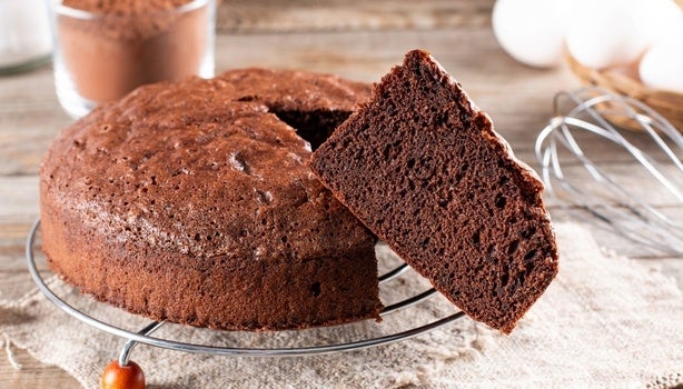Imagem de um bolo redondo de chocolate com uma fatia em evidência.
