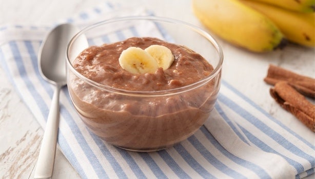 Imagem de um pote de vidro com doce de banana com cacau e rodelas de banana decorando.