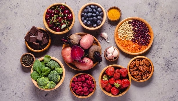 Tigelas com frutas, vegetais, sementes e chocolate amargo, representando alimentos ricos em antioxidantes naturais.
