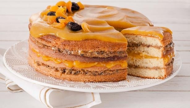 Bolo recheado de damasco, ameixa e doce de leite sobre um prato branco.