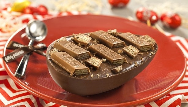 Prato vermelho com metade de um ovo de Páscoa recheado com kitkat em cima.