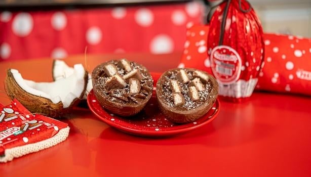 Ovo de Páscoa Prestígio recheado com chocolate e pedaços de coco, decorado com barrinhas Prestígio ao fundo.