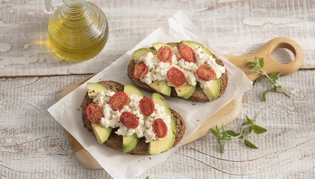 Duas torradas de avocado, patê de ricota e tomates.
