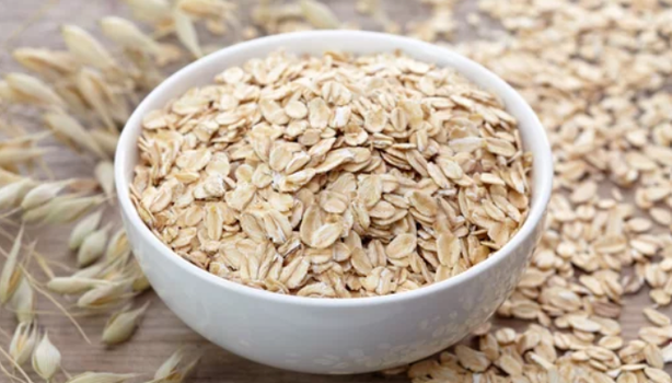 Bowl branco com aveia e grãos de aveia em volta.