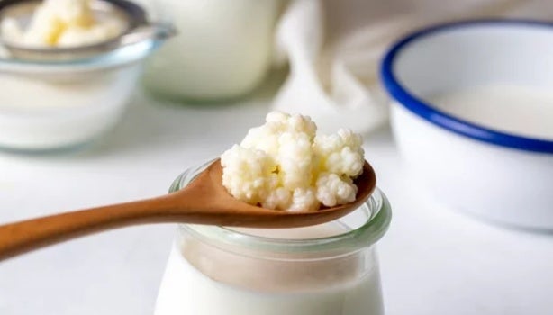 Colher de madeira com kefir sobre um copo de leite.