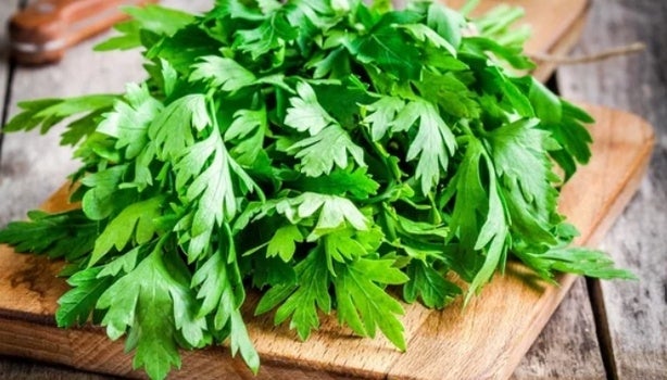 Folhas de salsa sobre tábua de madeira.