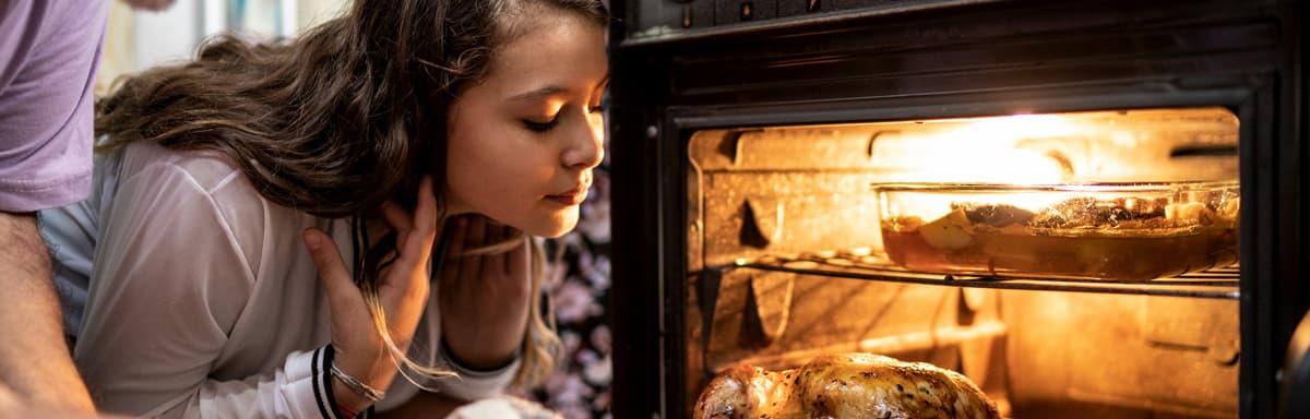 Receitas de Ceia de Natal: Homem colocando frango no forno , ao lado uma menina