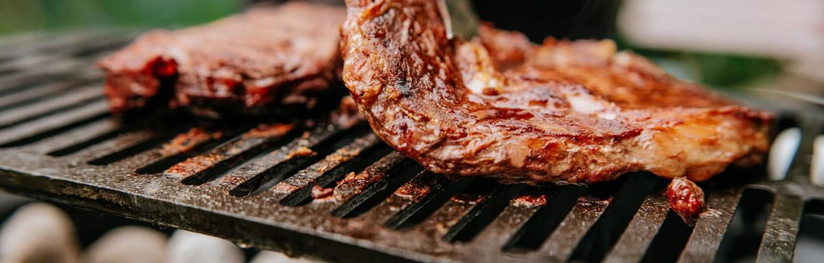 Cortes de Carne Bovina: uma pessoa colocando carne na grelha