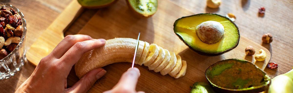 Safra de Março: uma pessoa cortando uma banana, com um abacate cortado do lado