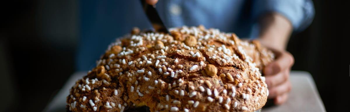 Colomba pascal sendo cortada por uma pessoa em cima de uma mesa