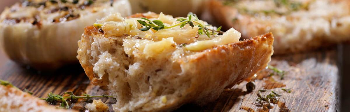 Pão de alho caseiro: Pedaço de pão de alho caseiro em cima de uma mesa de madeira