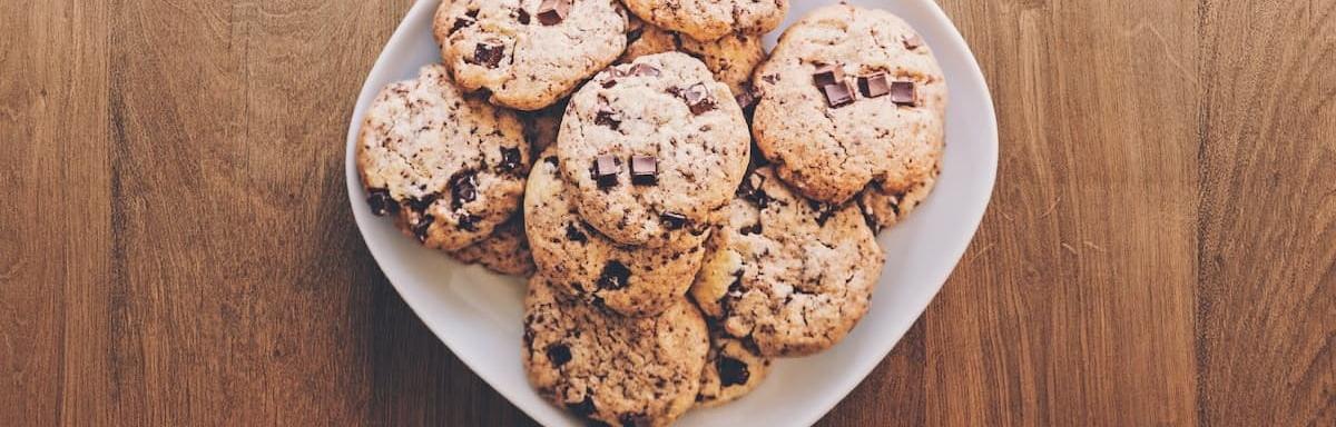 Lanches Rápidos:Vários cookies em um prato, em cima de uma mesa de madeira