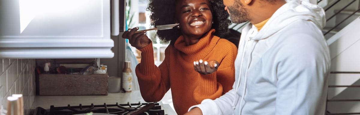 Utensílios Básicos de Cozinha: Mulher negra à esquerda oferecendo comida para o homem negro barbudo à esquerda