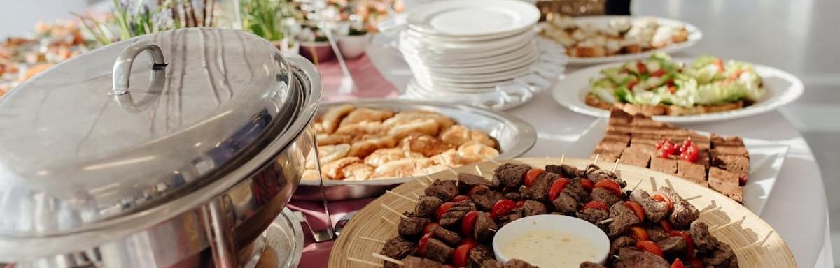 Banquete com espetinhos de carne, torradas, saladas e diversos outros pratos.