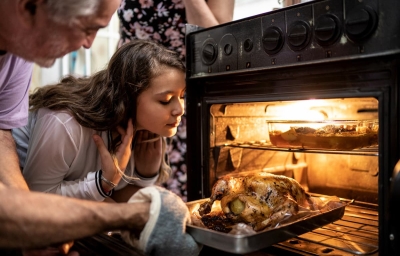 Receitas de Ceia de Natal: Homem colocando frango no forno , ao lado uma menina