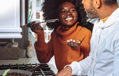 Utensílios Básicos de Cozinha: Mulher negra à esquerda oferecendo comida para o homem negro barbudo à esquerda