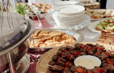 Banquete com espetinhos de carne, torradas, saladas e diversos outros pratos.