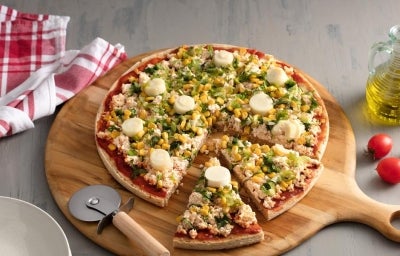 Pizza com duas fatias cortadas sobre uma tábua de madeira, abaixo da pizza tem um cortador e à direita azeite e dois tomates.