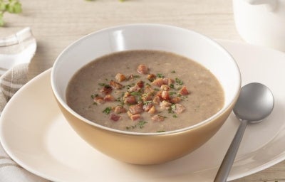 As melhores comidas de Inverno Sopa de feijão na tigela em cima de um prato, ao lado uma colher