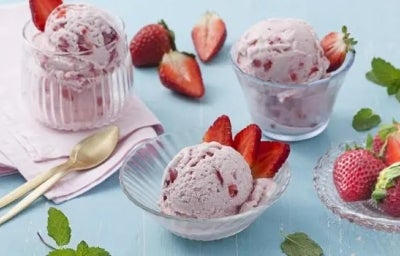 Imagem de 3 potinhos com sorvete de morango com pedaços e morangos e folhas de hortelã ao lado.