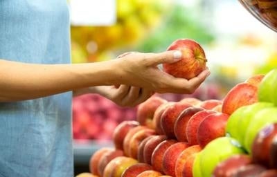Mão segurando uma maçã como se estivesse escolhendo frutas.