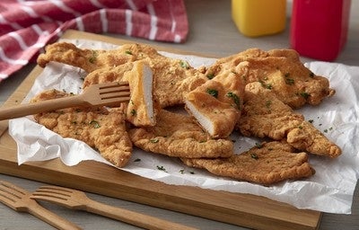 Filés de frango empanados e fritos, servidos em tábua de madeira com garfos de madeira e tempero verde por cima.