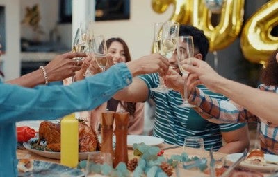 Pessoas brindando em uma mesa e ceia festiva.