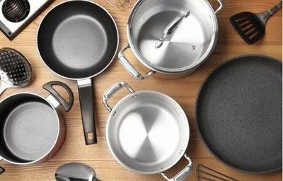 Conjunto de panelas e utensílios de cozinha organizados sobre bancada de madeira.