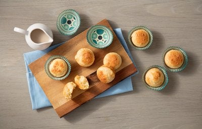 Pãezinhos sobre uma tábua de madeira e bule de chá.