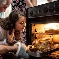 Receitas de Ceia de Natal: Homem colocando frango no forno , ao lado uma menina