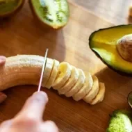 Safra de Março: uma pessoa cortando uma banana, com um abacate cortado do lado