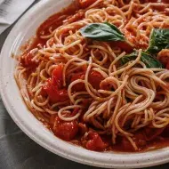 Opções de almoço rápido e fácil:Macarrão com molho de tomate no prato com um garfo ao lado em cima de uma mesa com pano cinza