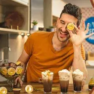 Imagem escrito 3 Bebidas com Dolce Gusto Alpino seguido do logo da marca e no lado esquerdo uma foto do Lucas com 3 bebidas.