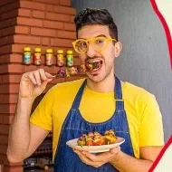 Lucas está comendo, vestindo uma camiseta amarela e um avental jeans. Também está escrito mix de Espetinhos e o logo de Maggi