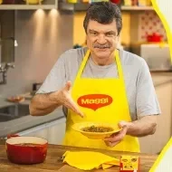 Imagem de um homem alto com bigode de avental segurando um prato amarelo e ao lado direito os dizeres e o logotipo de Maggi