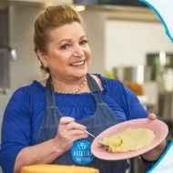 Imagem de uma mulher de avental jeans azul segurando um prato rosa com beijinho de coco e os dizeres do curso ao lado direito