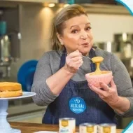 Imagem de uma mulher de avental jeans azul segurando um pote rosa com doce de leite e os dizeres do curso ao lado direito