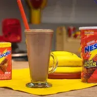 Imagem com um copo de bebida marrom e um canudo vermelho, lata de Nescau à esquerda, o texto à direita com logo de Nescau