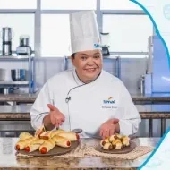 Montagem com a imagem de uma chefe com uniforme branco à esquerda e à direita o título da aula enroladinho de salsicha