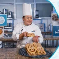 Montagem com a imagem de uma chefe com uniforme branco à esquerda e à direita o título da aula de pretzels