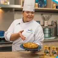 Montagem com a imagem de uma chefe com uniforme branco à esquerda e à direita o título da aula de empadão de frango