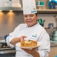 Montagem com a imagem de uma chefe com uniforme branco à esquerda e à direita o título da aula de quiche de queijos