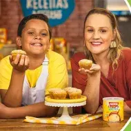 Montagem de uma foto de um menino e uma mulher loira, ambos segurando bolinhos, com os dizeres do programa à direita