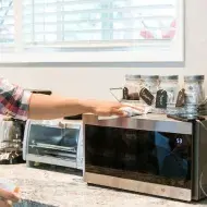Homem limpando o micro-ondas em sua cozinha
